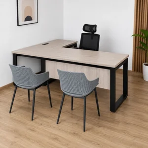 Escritorio en L de madera clara con estructura metálica negra, silla ergonómica y dos sillas de visita en oficina moderna.