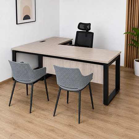 Escritorio en L de madera clara con estructura metálica negra, silla ergonómica y dos sillas de visita en oficina moderna.