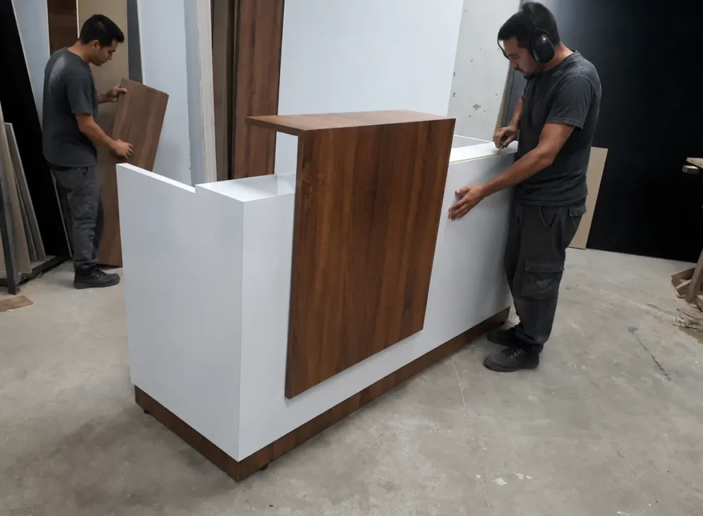 Trabajadores fabricando una recepción a medida en el taller de Muebles DyEG.