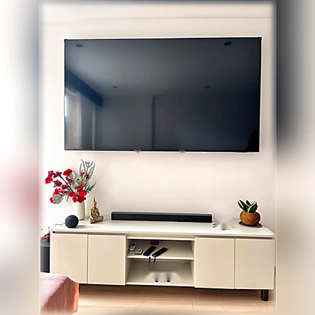 Mueble bajo blanco para televisor con puertas cerradas y estantes centrales abiertos, de Muebles Dyeg.