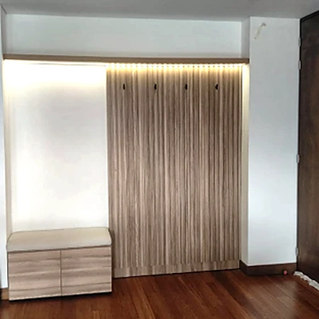 Panel decorativo de listones de madera con iluminación superior y módulo de almacenamiento lateral, de Muebles Dyeg.
